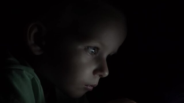 Little boy watching cartoon or playing games on smartphone at night. using your smartphone or tablet. Night shot.