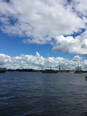 Water area of the Neva river, where there are warships with flags that arrived to participate in the naval parade in St. Petersburg against the background of the Peter and Paul fortress.