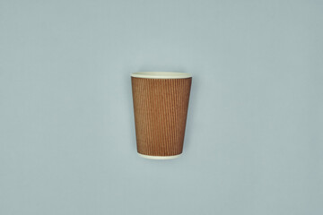 Paper cup in hand on a colored background. Eco-friendly materials in a coffee shop, biodegradable disposable tableware. Close up.