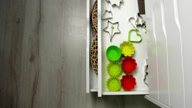 Closing of chest of drawers with different kitchen utensils, top view