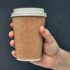 Paper cup in hand on a colored background. Eco-friendly materials in a coffee shop, biodegradable disposable tableware. Close up