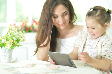 Happy mother and daughter using tablet together at home