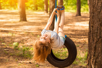 Happy active child girl playing on swing wheel in forest on sunny summer day. Preschool child...