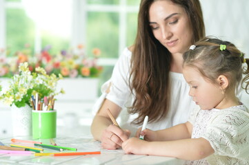 Cute girl with mother drawing at the table