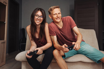 Happy guy and girl play video games on a video game console