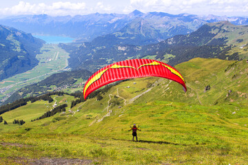 Paraglider flying over the field in the Alps mountain area Meiringen in Bern Oberland with Brienz lake at the background