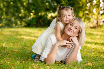 mom blonde with daughter in the park in summer in sunny weather
