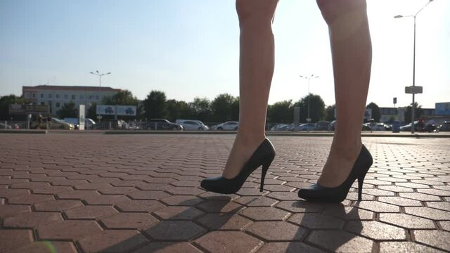Female legs in high heels shoes walking in the urban street. Feet of young business woman in high-heeled footwear going in the city. Girl stepping to work. Slow motion Close up