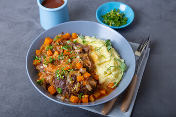Ossobuco. Veal (beef) shanks with mashed potatoes, gremolata and sauce. Traditional Italian dish. Close-up.