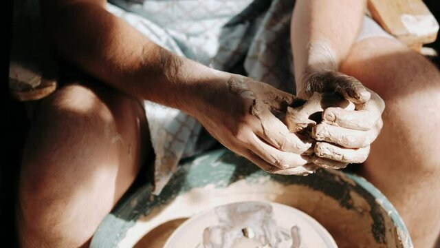 The master creates a white clay product. The master's hands close-up sculpt a clay product using a potter s wheel. The potter teaches his apprentice mastery.