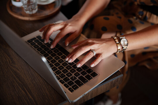 Young Woman Is Working On Computer, Typing On Laptop In Coffe Shop.