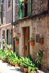 Fototapeta na wymiar The front of the house with hanging wires, ropes, flower pots and Windows with green shutters. city of Valdemossa. Majorca, Spain.