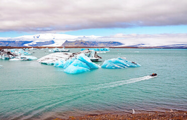 Icebergs in Jokulsarlon lagoon, Iceland, part of the Vatnajokull glacier national park. In the background the sunlit Hvannaldshnúkur, Iceland's highest peak.