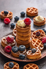 Traditional Belgian waffles with berries. Waffles with cream, raspberries and blueberries. Selective focus.