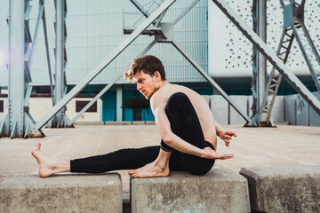 Young man  in the city in the yoga position ardha matsyendrasana stretching and relaxing her body and mind.