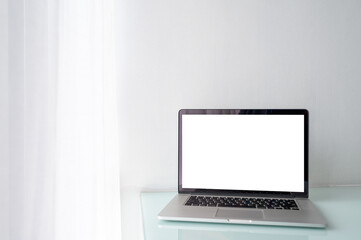 Blank screen of laptop computer on table with white wall and white curtain