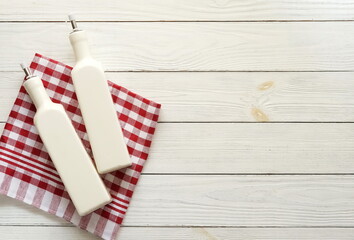 Checkered napkin and olive oil bottles maket template on white wooden background top view, copy space