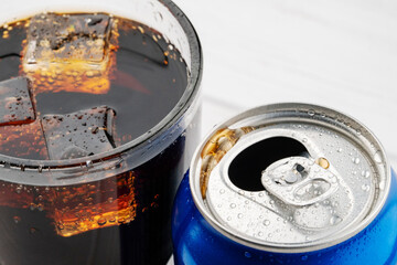 Open aluminum can and glass of cola isolated on white