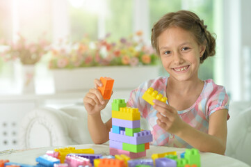 Cute girl playing with colorful plastic blocks
