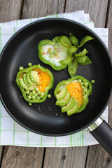 Healthy Breakfast of fried eggs in pepper rings with avocado and green peas