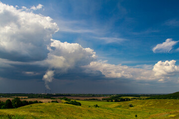 Power plant with a smoking chimney on the background of a summer landscape