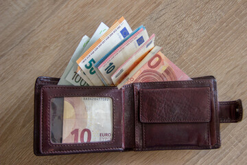 A lot of euro currency lies in a leather wallet.
