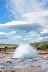 GEYSIR, ICELAND: Early eruption of Strokkur geyser, observed by many tourists, on a day with remarkable cloudscape. 