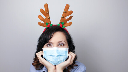 Woman wearing protection face mask against coronavirus. Woman in a mask with Christmas headband. We...