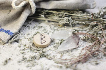 Scandinavian wooden rune Berkana, Beorc,Bjarkan on a rough linen cloth with amethyst crystalline, rock crystal and dried wormwood