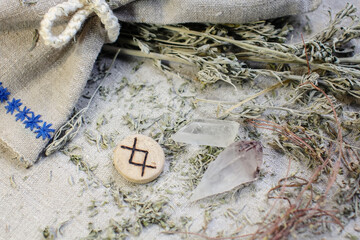 Scandinavian wooden rune Ingwaz, Inguz on a rough linen cloth with amethyst crystalline, rock...
