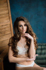 Fototapeta premium Beautiful woman in lingerie showing long legs sexy pose standing at bed over her bedroom near big window. Bride boudoir. Wedding morning.