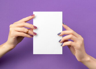 Beautiful womans hand with manicure holding postcard