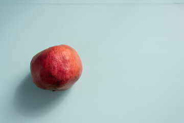 Pomegranate fresh fruit uncut green desk aqua menthe with copy space