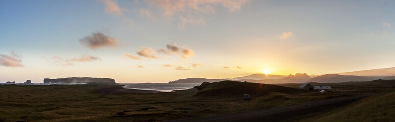 Obraz premium Sunset behind Eyjafjallajokull volcano, at Reynisfjara beach near Vik in Southern Iceland; to the left the promontory of Dyrholaey