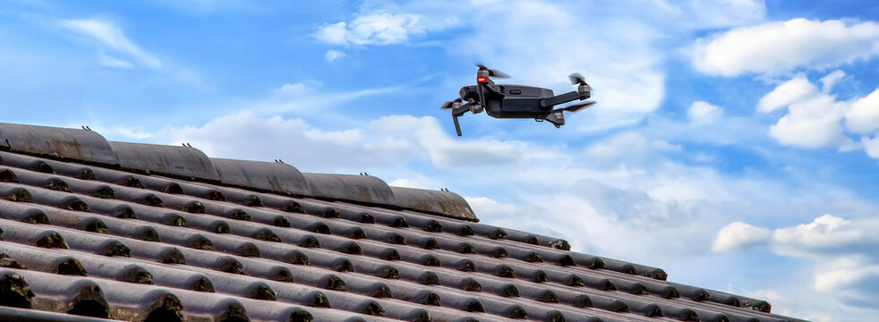 Drone in the air inspecting the roof over the house. Close-up of drone and roof.