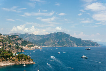 View from Conca dei Marini on Amalfi bay, Luxury boats traffic, ocean liner, fishing boats, tourist season. watercraft. Mountains and houses, buildings. Summer day. Amalfitana Italy