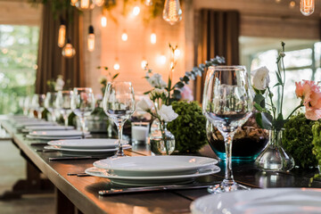 Wedding reception table with Edison bulbs and decor of greenery. Decoe. Wedding table setting