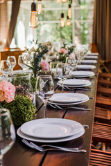 Wedding reception table with Edison bulbs and decor of greenery. Decoe. Wedding table setting