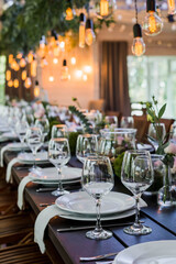 Wedding reception table with Edison bulbs and decor of greenery. Decoe. Wedding table setting