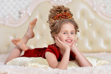 Cute girl in red dress lying on bed