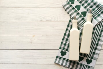 Checkered napkin and olive oil bottles maket template on white wooden background top view, copy space