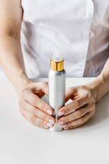 Obraz na płótnie Canvas White and golden cream bottle in woman's hand. Cosmetologist holding spin care product. 