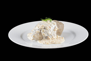Potato dumpling with meat and sauce on black background.