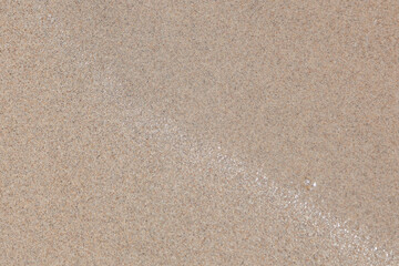 Close-up of a river bank made of beige-gray sand with particles of old shells of shells, design of a pattern, material for making a building material - concrete.