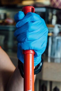 Woman With Blue Gloves Cleaning The Floor Of A Restaurant With A Mop