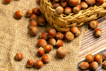 Hazelnuts in a wicker basket and hazelnuts scattered on a background of homespun fabric with a rough texture. Close up.