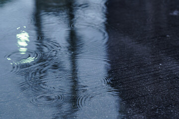 Rain drops rippling in a puddle. the street light refected in the puddle of water