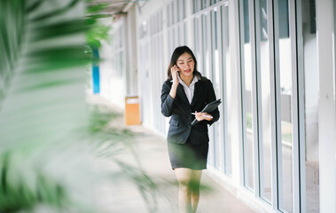 Beautiful asian business woman talking on cellphone while walking outdoor