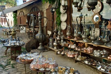 A display of traditional Turkish souvenirs of bronze and copper handcrafted cookware and souvenir hanging from the wall on the pavement waiting for customers. Safranbolu UNESCO Turkey