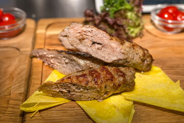Grilled sausage cut into pieces lies on napkins wooden cutting board